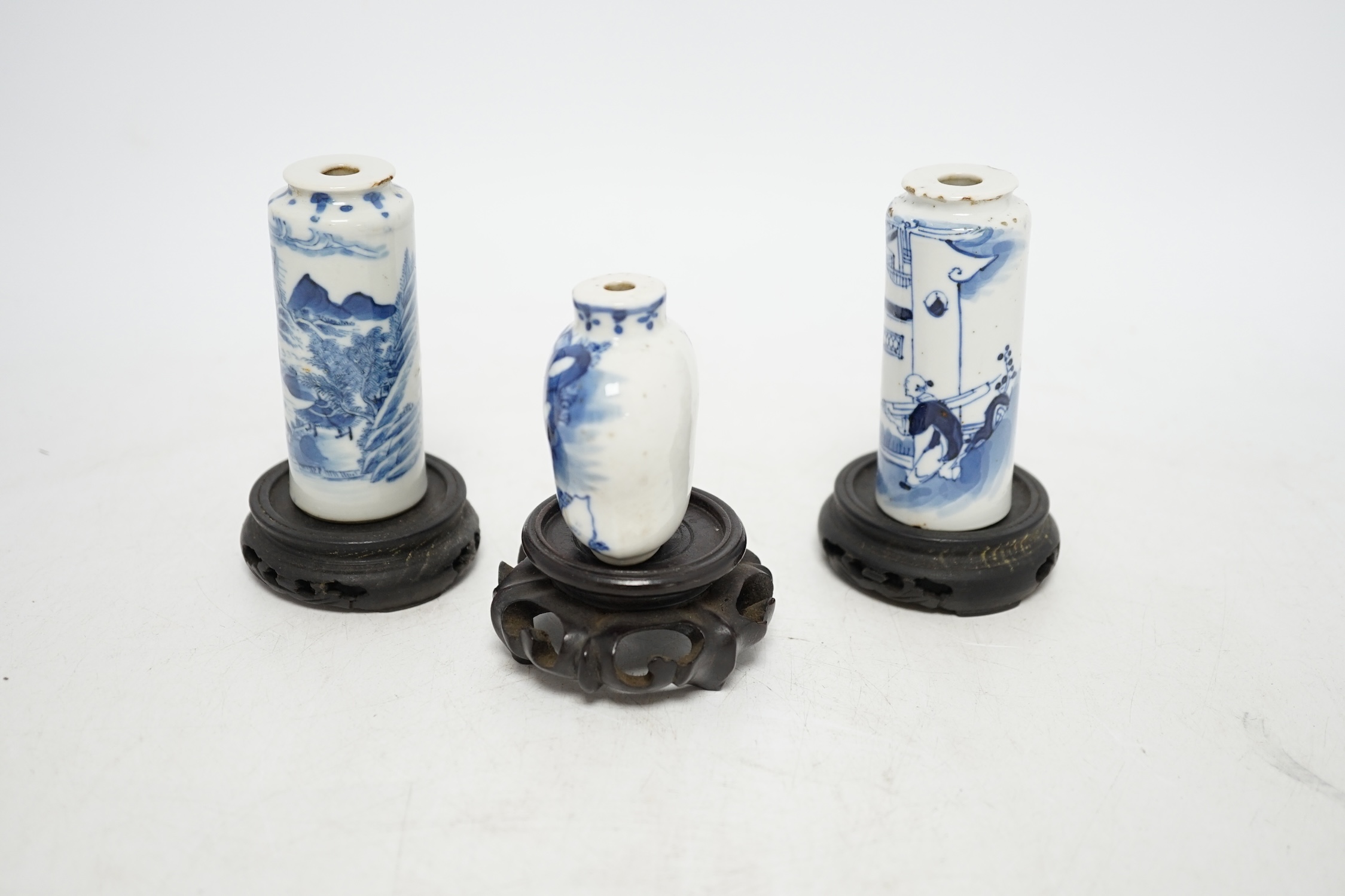 Three Chinese blue and white snuff bottles and three hardwood stands, largest 8cm high. Condition - poor to fair